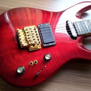 Esche, 4-Teilig, Ahornfurnier (mit einem erstaunlich starken 3-D Effekt). Sehr geil verarbeitet und sehr dünn und sauber lackiert.
DiMarzio Evolution mit 3-Loch Kappe und Sustainiac.
Single-Locking Floyd Rose.