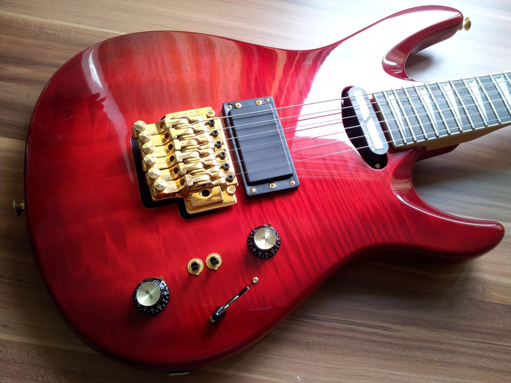 Esche, 4-Teilig, Ahornfurnier (mit einem erstaunlich starken 3-D Effekt). Sehr geil verarbeitet und sehr dünn und sauber lackiert.
DiMarzio Evolution mit 3-Loch Kappe und Sustainiac.
Single-Locking Floyd Rose.