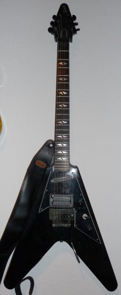 Gibson V90

Ich weiss noch wie ich damals, meiner schrottigen Hohner ST Special entwachsen, auf der Suche nach meiner ersten "richtigen" E-Gitarre war und in einem Gitarrenladen in Frankfurt so eine Flying V in der Hand hatte. Das Teil hatte mich einfach umgehauen. Leider konnte ich mir so ein Ding überhaupt nicht im entferntesten leisten, aber seitdem musste ich eine Flying V haben. Unbedingt! Und hab dann letztlich eine gebrauchte ´72 Gibson Flying V gekauft, die in einem erbärmlichen Zustand war.
Naja, als dieses Ding vor ein paar Jahren auf eBay zum Verkauf stand, musste ich sie natürlich haben! Sie klingt auch für meinen Geschmack heute immernoch super! Sie hat nur zwei Probleme: sie ist sauschwer und eigentlich total kopflastig. Daher hab ich mir erlaubt, einen kleinen Ausleger hinten anzuschrauben, um einen günstigeren Punkt für die Gurtbefestigung zu schaffen. Deshalb sieht das so komisch aus mit dem Gurt da. ;-) Aber es wirkt!

Mahagonie-Korpus, Ahornhals (!), Setneck, Ebenholz Griffbrett, Pickups und Hardware original.