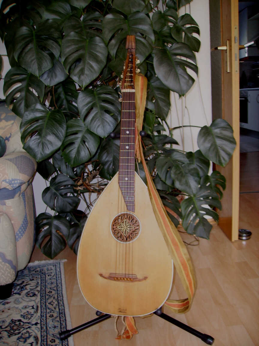 Gitarrenlaute, ca 1930 (geschätzt) Vorderseite mit eingeleimter Schalllochrosette, Brandstempel "Deutsche Meister"

Decke, Korpus Fichte. Original Mechaniken. Risse in Decke und Korpus geschlossen, mehrfach gebrochener Kopf geleimt und mit gesperrten Zügen stabilisiert. Das Instrument ist in Korpus und Hals gebeizt und anschließend gewachst. Sattelbreite 44mm, Mensur 590mm. Saitenabstand über Bund 9 ca. 4,5mm. Das Instrument hat einen rustikalen Klang und wird eher selten gespielt

Falls jemand genaueres zu dem abgebildeten Instrument weiß (Baujahr, Hersteller, etc.), bitte unbedingt an mich weitergeben.