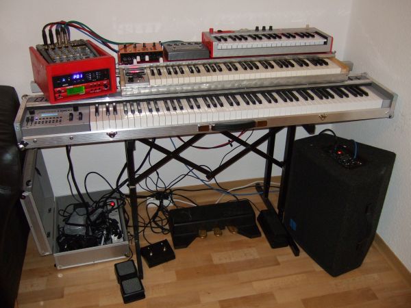 Hier ist alles aufgebaut. 

Auf dem Orgelkeyboard (Selbstbau aus Doepfer MKE und Fatar Waterfalltastatur) liegt die Voce V5, Ventilator und Alesis Micron.

Als Monitor verwende ich einen KME FM 1122 AE.

Unten sind noch Expression-Pedal (u.a. für WahWah über Boss VF1), 2-fach Fussschalter für Leslie Brake/Slow/Fast am Ventilator, GEM 3-Fach Pedal und Volume-Pedal für die Orgen zu sehen.

Über das LMK4+ schalte ich die Presets von RP-X und Boss VF1 um und steuere die Effektparameter (z.B. Mod-Wheel -> Tremolospeed, Drehknopf -> Tremolotiefe, Sostenuto-Pedal -> WahWah on/off, Expression-Pedal -> WahWah)

Ausserdem leite ich das Sustain-Pedal über das LMK4+ über den 2. Midi-Out zum Micron weiter.